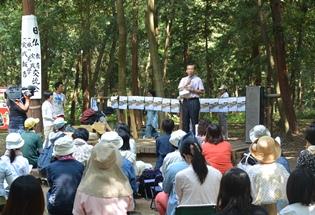 中沢地内の雑木林で行われた、けやの森学園主催の日仏教育実践交流会の挨拶の写真