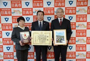 高麗川中学校の山崎恵美子先生(左側)と大里治泰校長先生(右側)と市長の写真