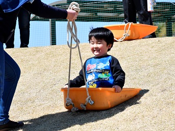 芝生の上をそりで降りる男の子