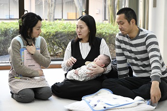 保健師に育児の相談をしている1組の夫婦の様子