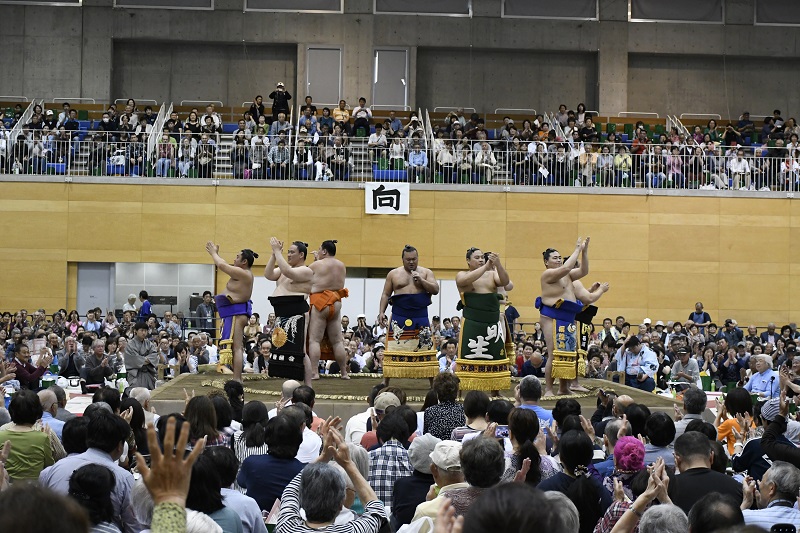 力士たちが土俵の上で歌を歌っている様子