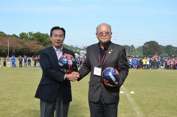 記念ボールの交換をする日高市長と烏山市キムホン団長の写真