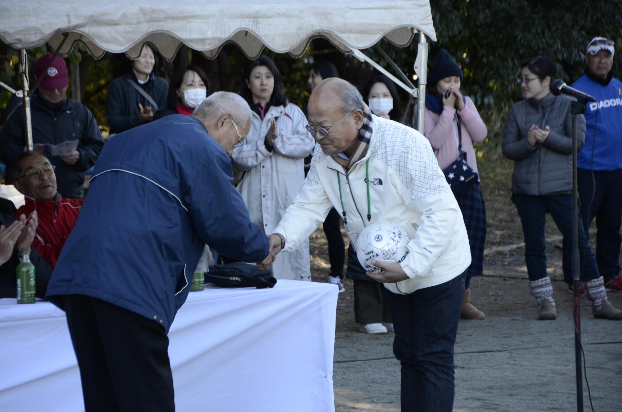 記念ボールを交換する日高市スポーツ少年団本部長と烏山市交流協会長