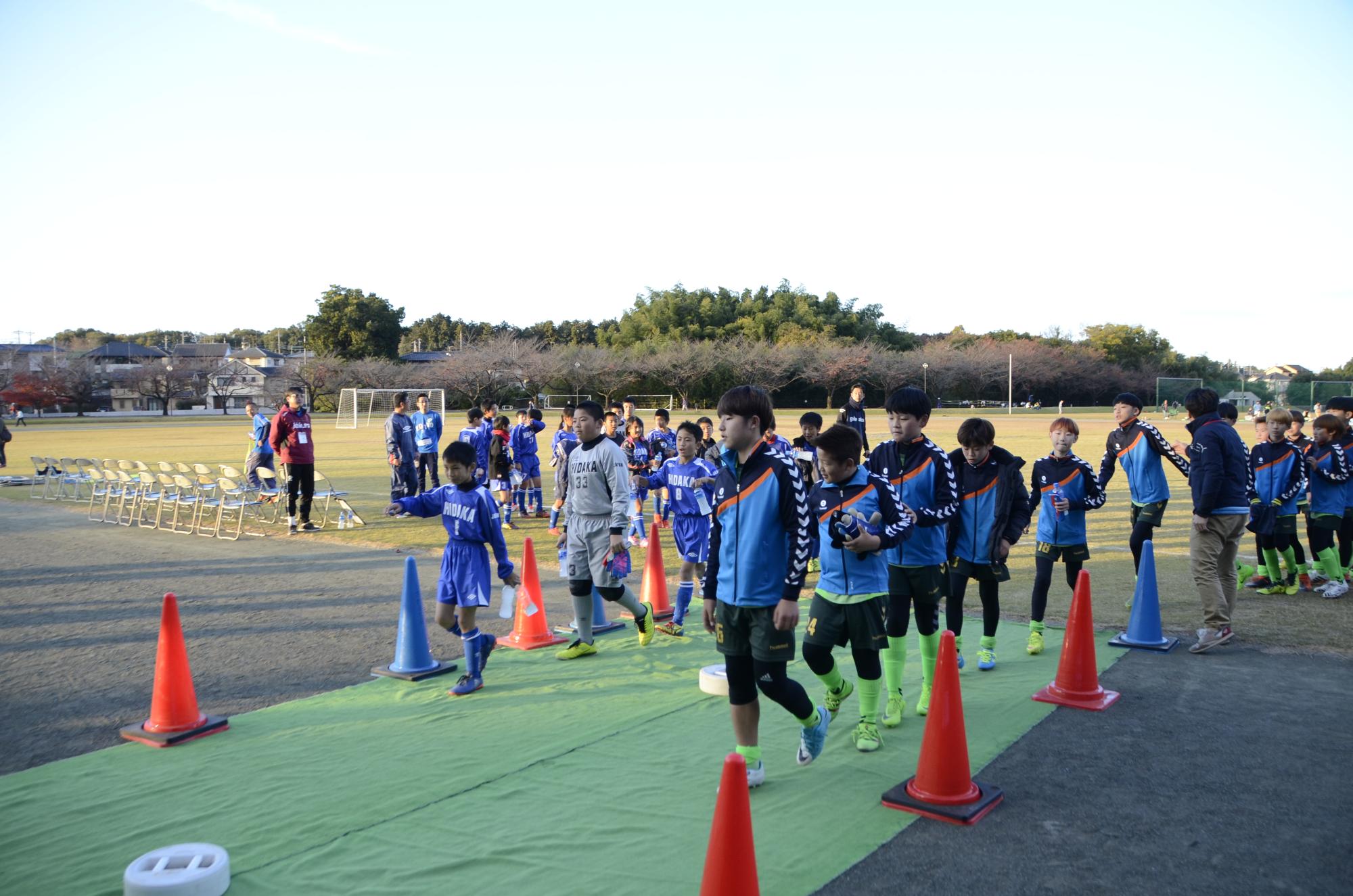 試合後拍手で見送られる両市選手たちの写真