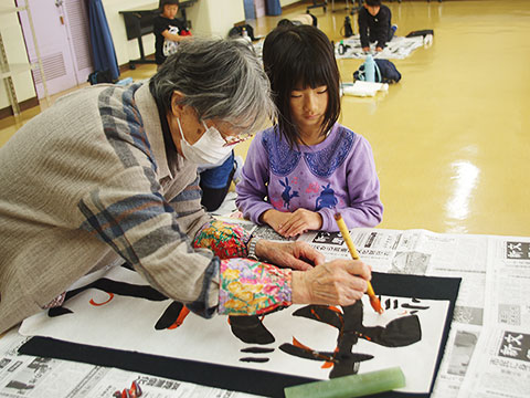 講師に書き初めの朱書きをしてもらっている子ども