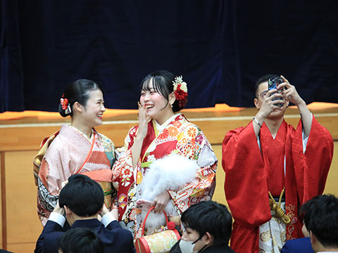 笑顔で談笑する振袖姿の女性たちと袴姿で写真を撮る男性
