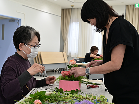講師のフラワーアレンジメントのお手本を見ている女性
