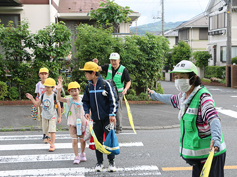 交通指導員に安全を確保してもらい、横断歩道を渡る子どもたち