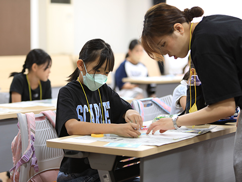 講師にパステルを使った絵の描きかたを教えてもらっている子ども