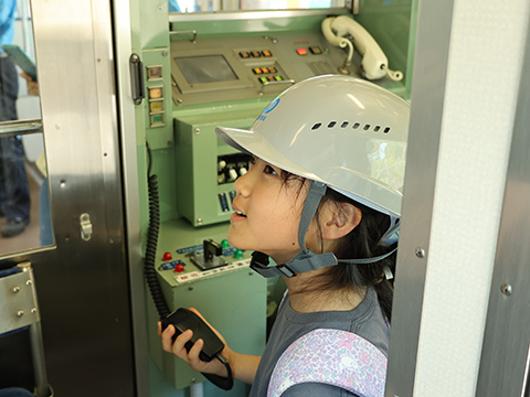 電車の運転席で機器に触れている子ども