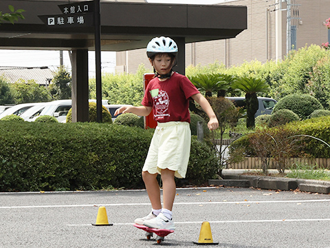 三角コーンを避けながらブレイブボードに乗っている子ども