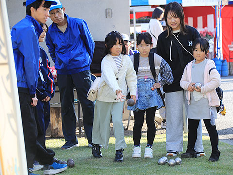 ボールを投げている子ども。見守る家族とスタッフ