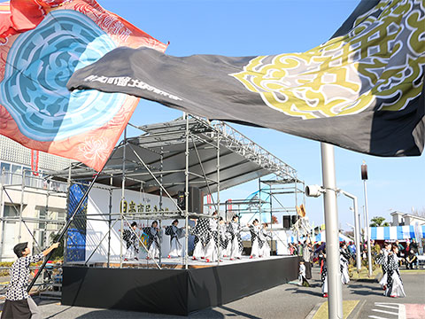 大きな旗とともにステージ上でよさこいを踊る参加者