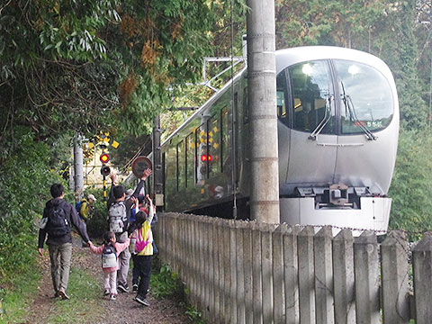 道沿いを走る特急列車に手を振る子どもたち