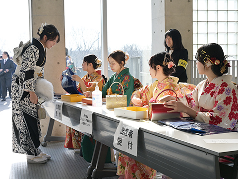 受け付けを行う振袖姿の女性