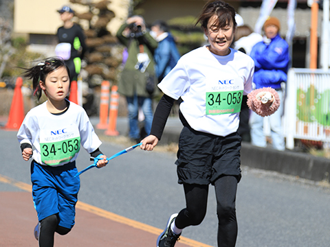 たすきを握り合いながら走る親子
